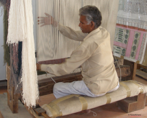 Man sits at loom and weaves